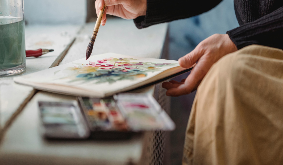 woman holding watercolor and pallet with paintbrush